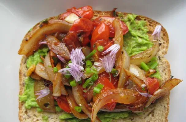 Tostada de aguacate con cebolla dulce caramelizada, tomates uva, cebollino fresco y flores de cebollino