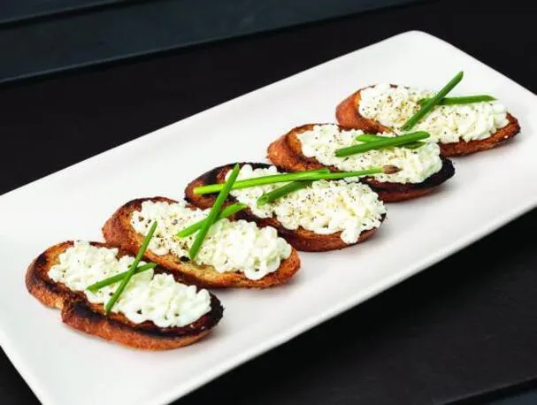 Queso de cabra con miel batida sobre crostini a la parrilla